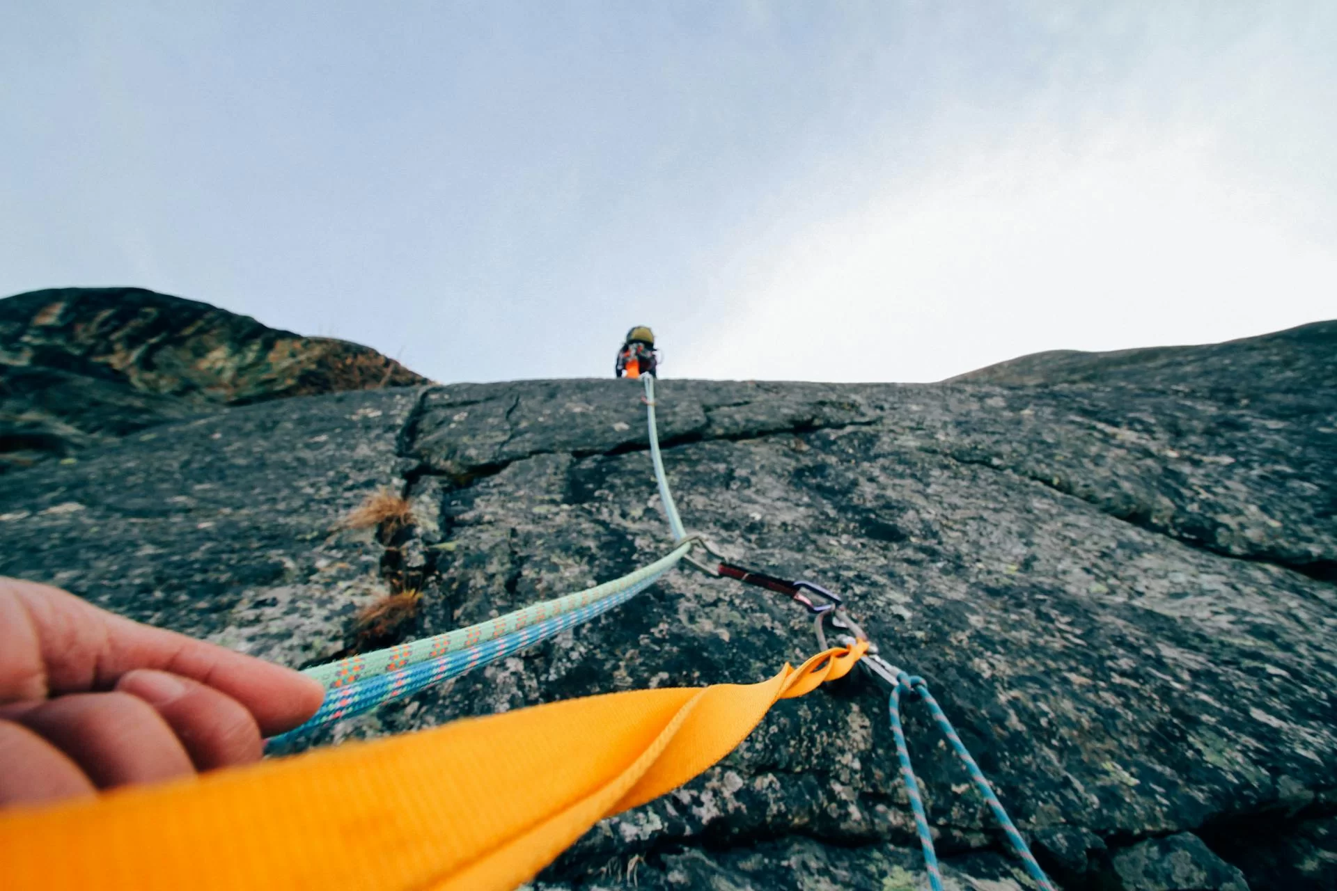 a rock climber helping another rock climber up a mountain